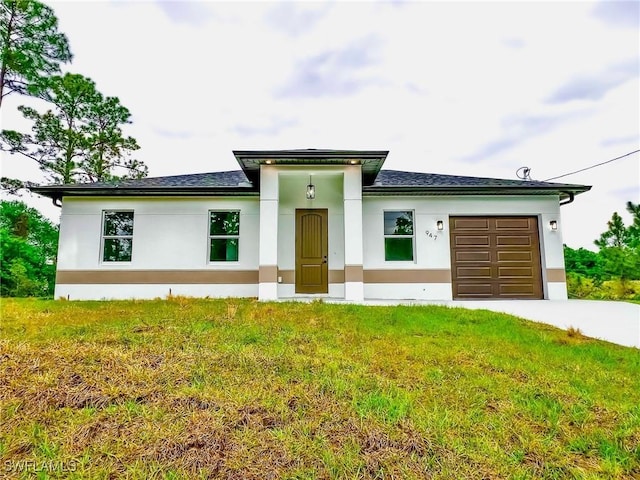 prairie-style house with a garage, a front lawn, concrete driveway, and stucco siding