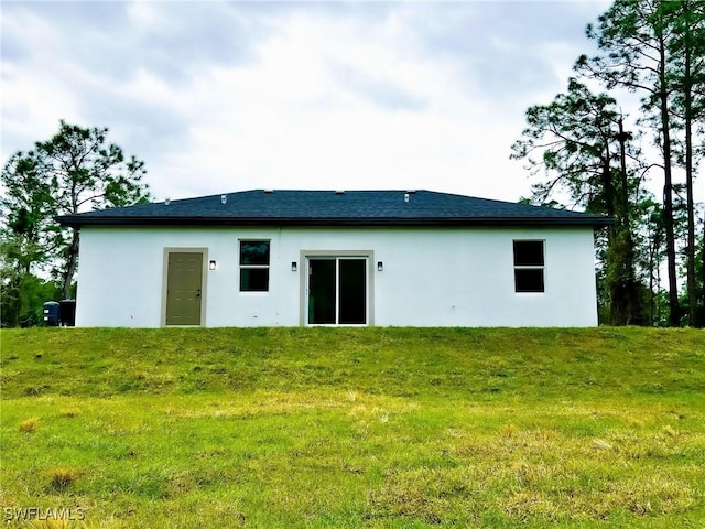 rear view of house with a yard and stucco siding