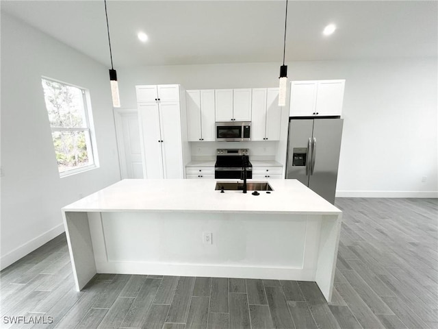 kitchen with stainless steel appliances, an island with sink, and wood finished floors