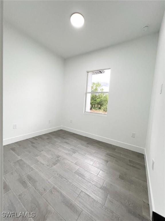 empty room with baseboards and wood finished floors