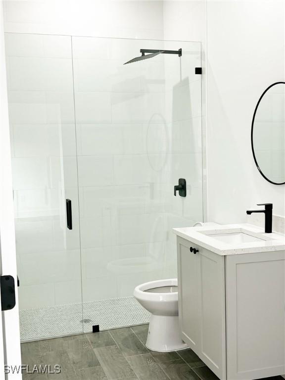 bathroom with toilet, a shower stall, and vanity