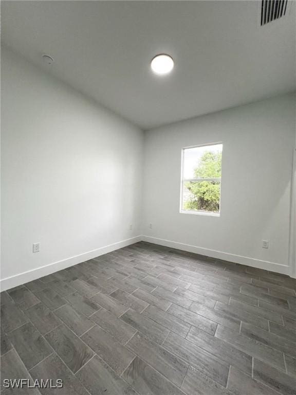 spare room featuring visible vents, dark wood finished floors, and baseboards