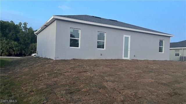 back of property with roof with shingles and stucco siding