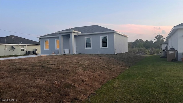 back of house at dusk featuring a lawn