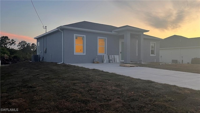 back of property with central AC, a yard, and stucco siding