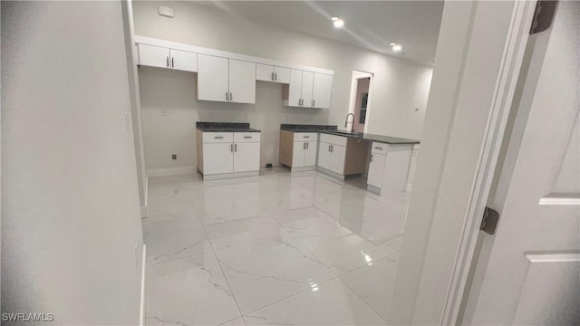 kitchen with recessed lighting, a sink, baseboards, white cabinets, and marble finish floor