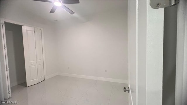 unfurnished bedroom featuring marble finish floor, ceiling fan, baseboards, and a closet