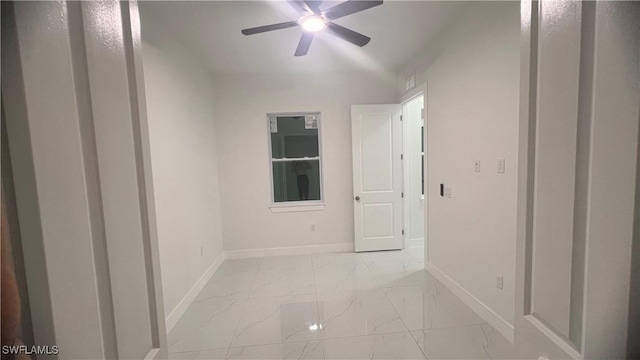 unfurnished room featuring marble finish floor, ceiling fan, and baseboards