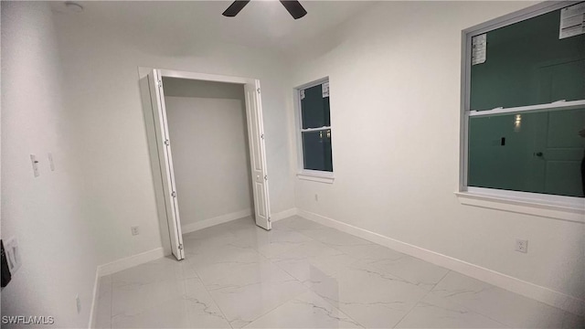 unfurnished bedroom featuring marble finish floor, a ceiling fan, and baseboards