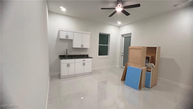 kitchen featuring ceiling fan, white cabinetry, baseboards, marble finish floor, and dark countertops