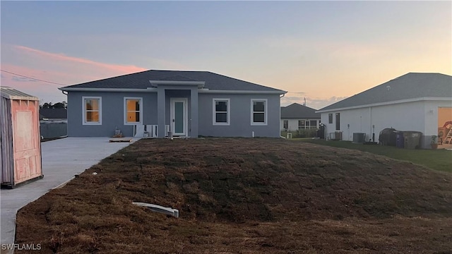 view of front facade with central AC, a patio, a front lawn, and stucco siding