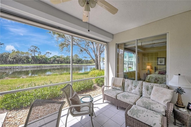 sunroom / solarium featuring a water view and ceiling fan