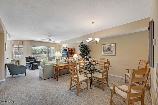 dining room with a textured ceiling, ceiling fan with notable chandelier, baseboards, and light colored carpet