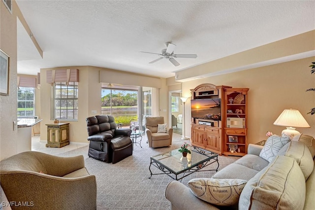 living area with light carpet, ceiling fan, a textured ceiling, and a wealth of natural light