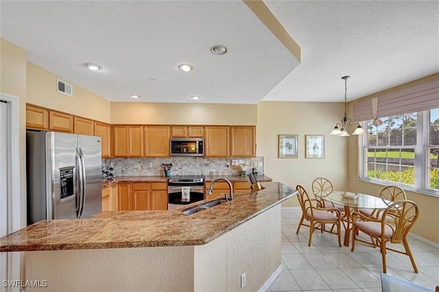 kitchen with stainless steel appliances, visible vents, decorative backsplash, a sink, and light stone countertops