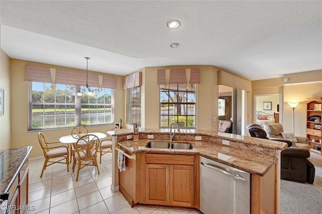 kitchen with light tile patterned floors, open floor plan, light stone countertops, stainless steel dishwasher, and a sink