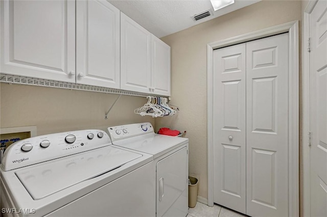 laundry area with visible vents, light tile patterned floors, independent washer and dryer, and cabinet space