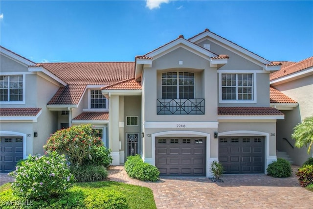 view of front of property with driveway, a tile roof, an attached garage, and stucco siding