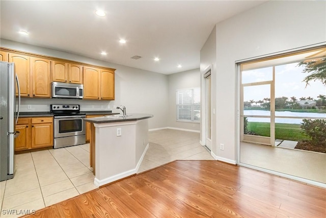 kitchen featuring light tile patterned floors, stainless steel appliances, dark countertops, recessed lighting, and a sink