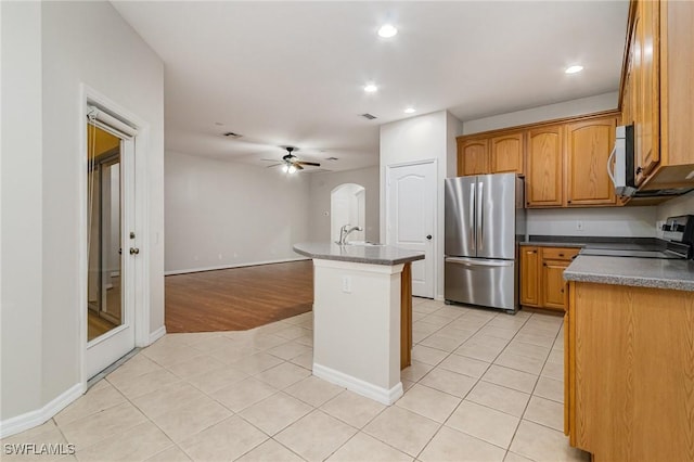 kitchen with light tile patterned floors, recessed lighting, stainless steel appliances, a sink, and dark countertops