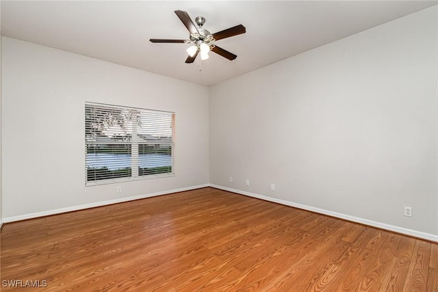 spare room with wood finished floors, a ceiling fan, and baseboards