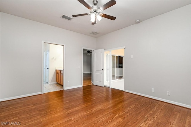 unfurnished bedroom featuring baseboards, ensuite bath, visible vents, and light wood-style floors