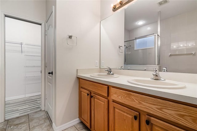 full bathroom with tile patterned flooring, visible vents, a sink, and a shower stall