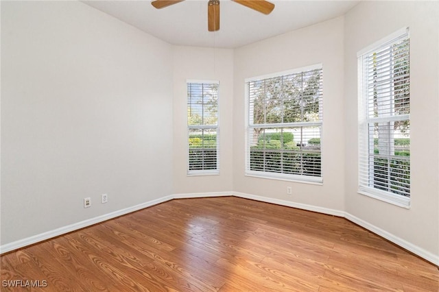 spare room with a healthy amount of sunlight, ceiling fan, baseboards, and wood finished floors