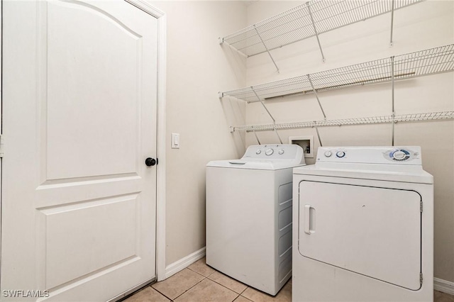 laundry room with laundry area, light tile patterned flooring, washing machine and clothes dryer, and baseboards