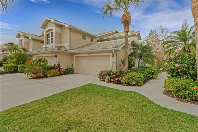 mediterranean / spanish house featuring driveway, a tiled roof, a front lawn, and stucco siding