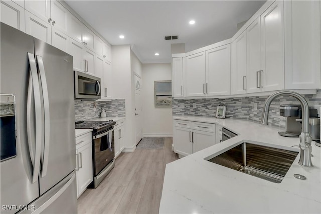 kitchen featuring light stone counters, a sink, visible vents, white cabinets, and appliances with stainless steel finishes