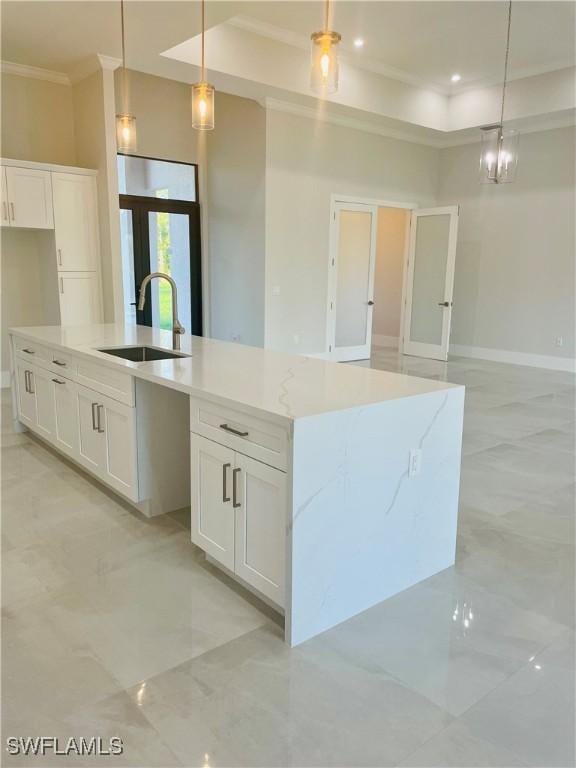 kitchen featuring ornamental molding, marble finish floor, a large island with sink, white cabinetry, and a sink