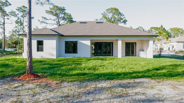 back of house featuring a shingled roof, a lawn, and stucco siding