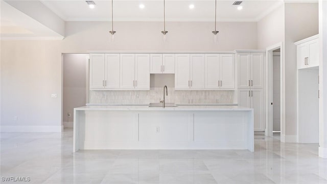 kitchen with tasteful backsplash, an island with sink, light countertops, white cabinetry, and a sink