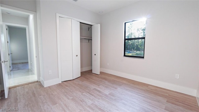 unfurnished bedroom with a closet, baseboards, and wood finished floors