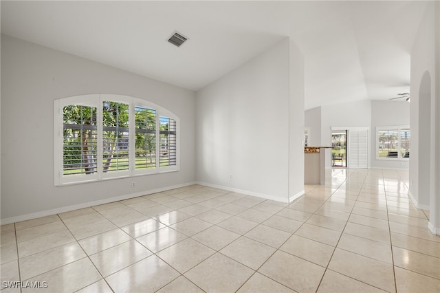 empty room featuring vaulted ceiling, light tile patterned flooring, visible vents, and baseboards