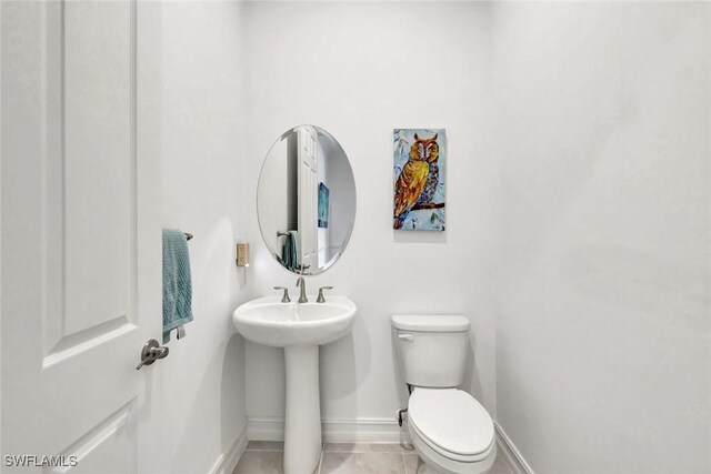 bathroom with baseboards, toilet, and tile patterned floors