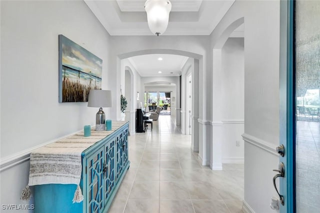 corridor featuring light tile patterned floors, baseboards, arched walkways, and crown molding