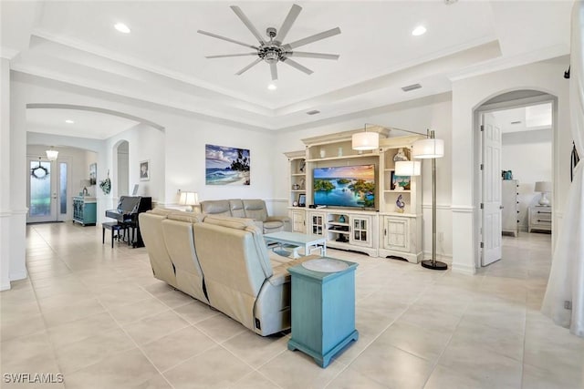 living area with arched walkways, light tile patterned floors, recessed lighting, a raised ceiling, and crown molding