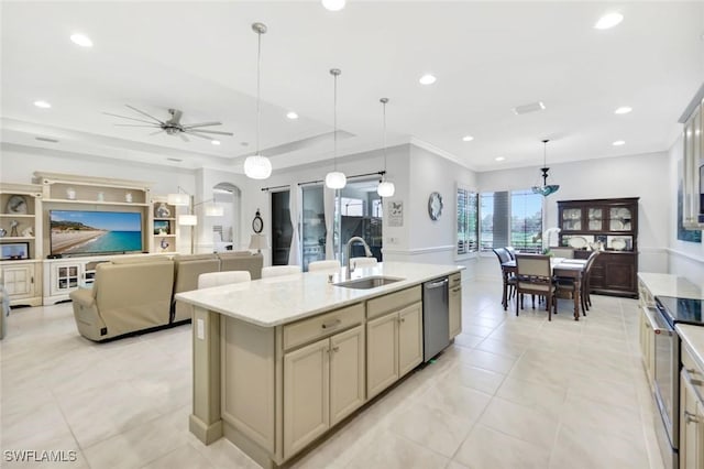 kitchen with arched walkways, a sink, appliances with stainless steel finishes, a center island with sink, and pendant lighting