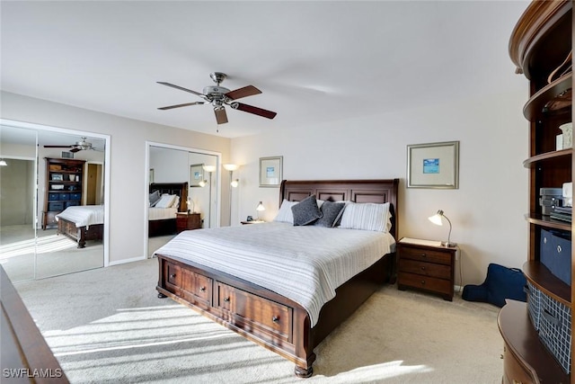 bedroom with baseboards, a ceiling fan, light colored carpet, and multiple closets