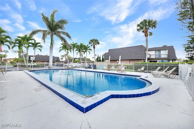 pool with a patio area and fence