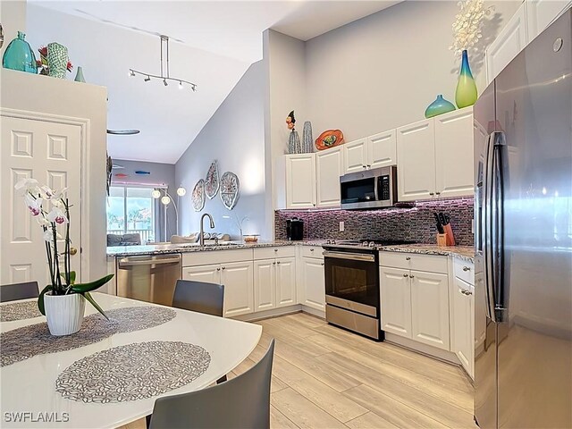 kitchen featuring a sink, light wood-style floors, appliances with stainless steel finishes, white cabinetry, and tasteful backsplash