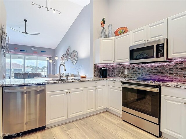 kitchen with a sink, stainless steel appliances, light stone counters, and tasteful backsplash