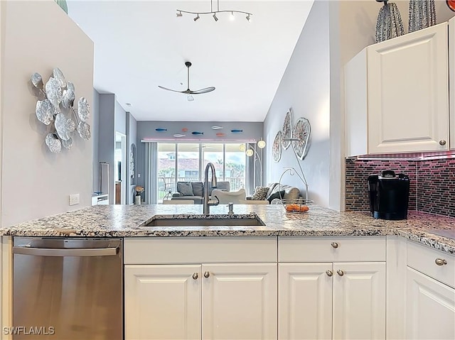 kitchen with a sink, stainless steel dishwasher, open floor plan, white cabinetry, and decorative backsplash