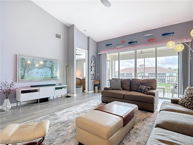 living area with visible vents, baseboards, high vaulted ceiling, and wood finished floors