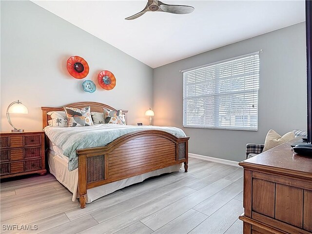 bedroom with baseboards, light wood-style flooring, a ceiling fan, and vaulted ceiling