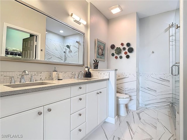 bathroom featuring marble finish floor, toilet, a shower stall, and a sink