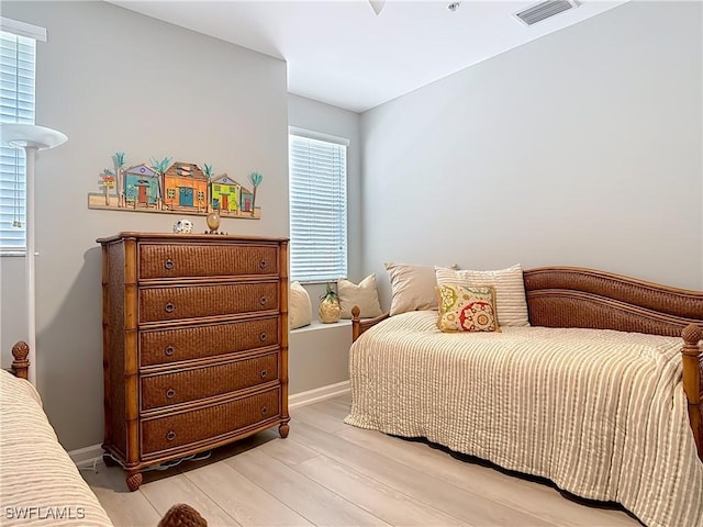 bedroom featuring visible vents, multiple windows, baseboards, and light wood finished floors