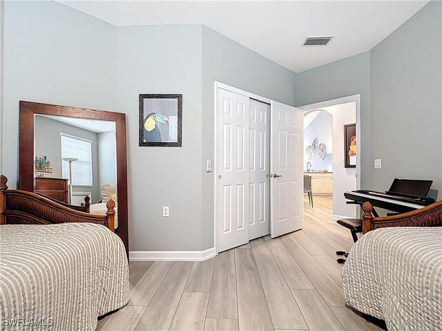 bedroom featuring light wood-type flooring, visible vents, baseboards, and a closet